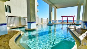 Uma área de piscina com hidromassagem, um solário e vista para o oceano.