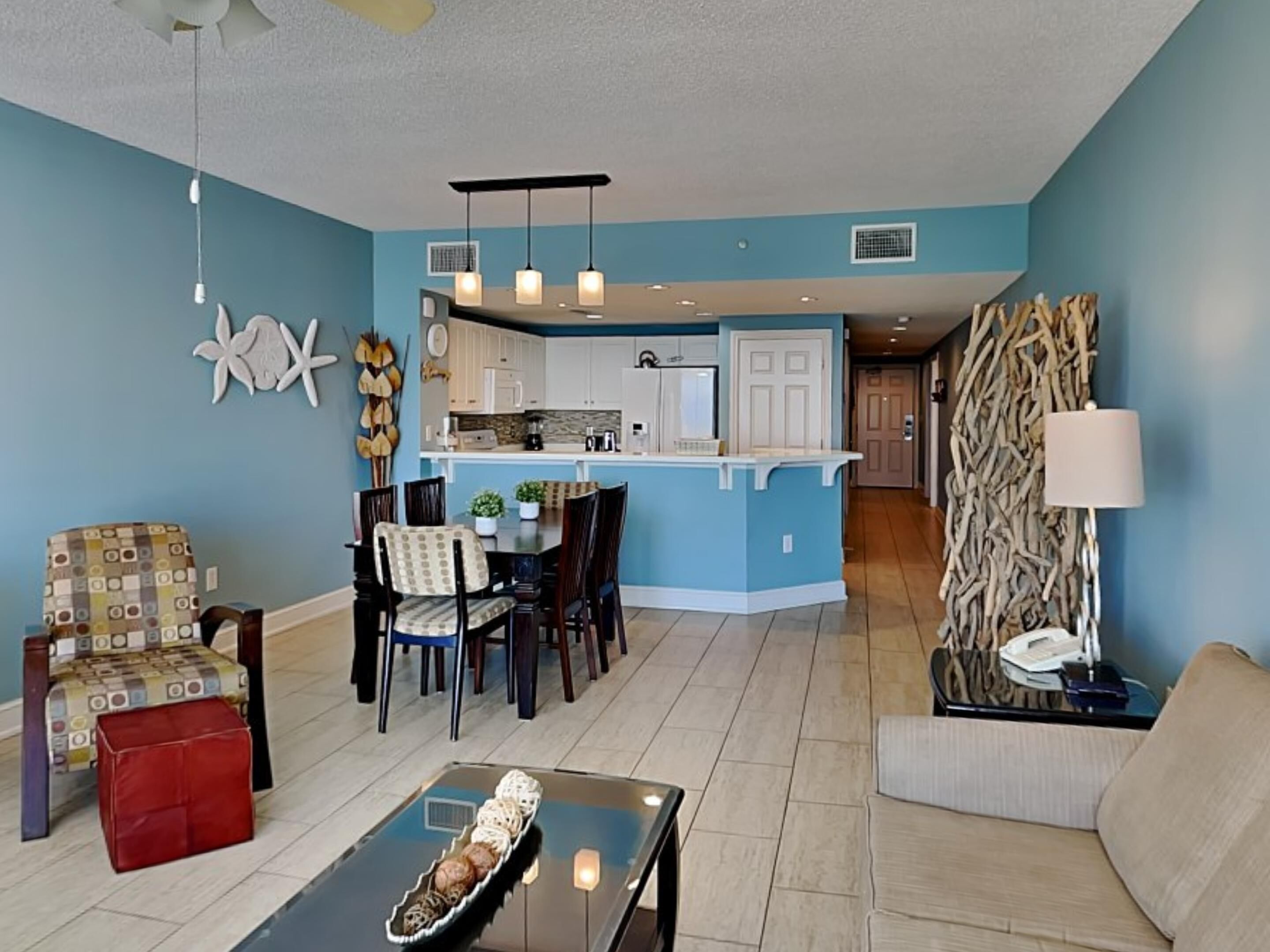 A modern living room with a dining area, a kitchen, and a hallway.