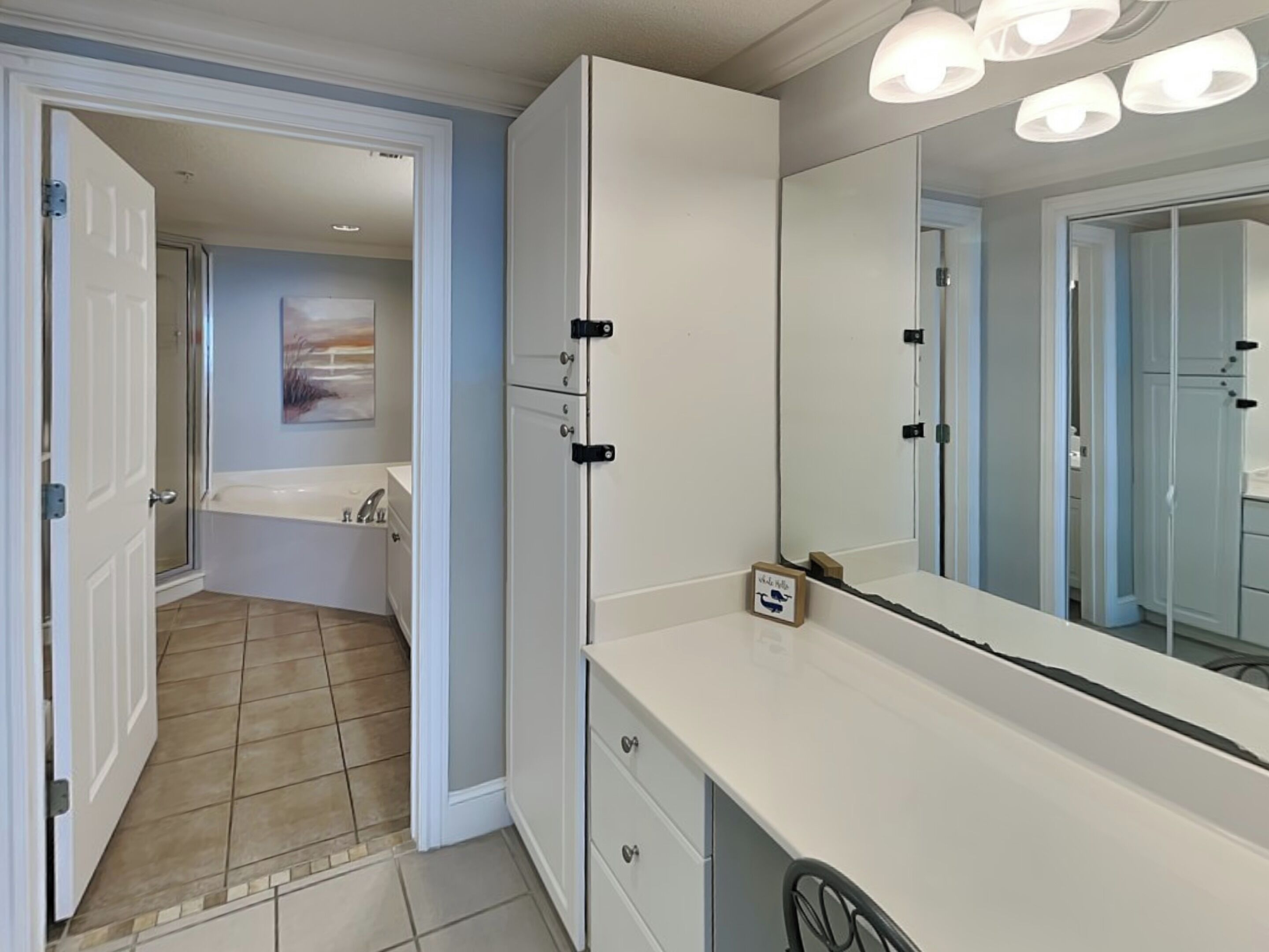 A bathroom with a white vanity, a large mirror, and a shower area visible through an open door.