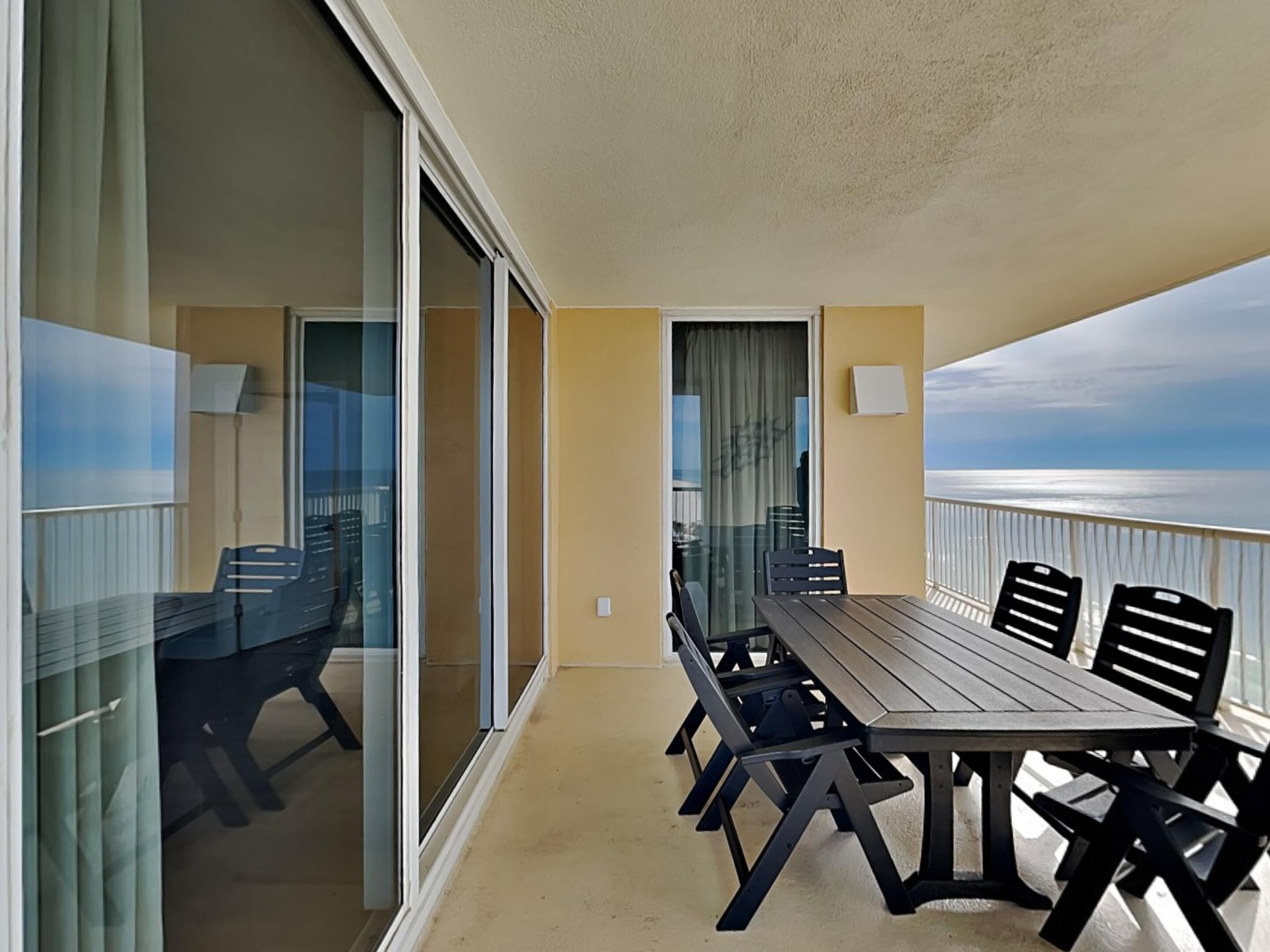 Un balcon avec une table et des chaises, une vue sur l’océan et une porte-fenêtre coulissante.