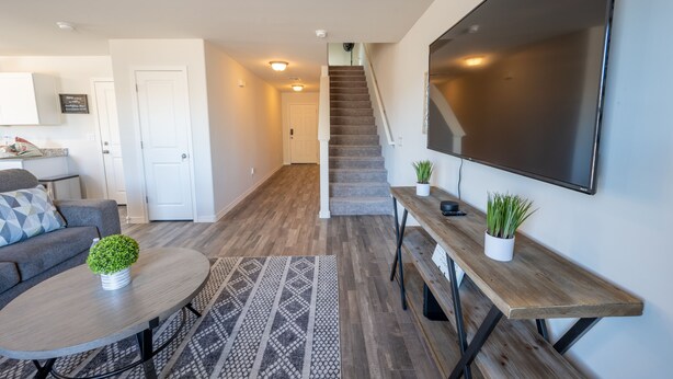Een moderne woonkamer met een bank, salontafel en een televisie aan de muur.