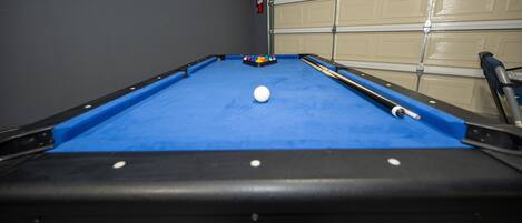 Ein Billardtisch mit einer weißen Spielkugel, blauem Filz und schwarzen Rändern.