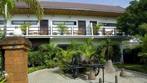 A building with a balcony, a stone pillar, and a cart with wheels. - Sekla Villa Angkor (Siem Reap)
