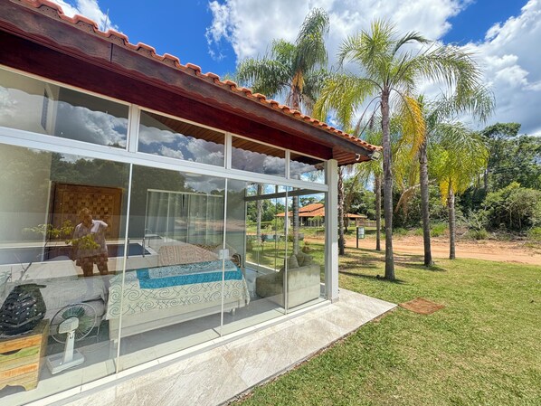 Una casa moderna amb una gran finestra de vidre, un teulat enrajolat i un jardí amb palmars.