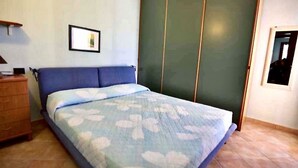 Ein Schlafzimmer mit einem Bett, einem Schminktisch, einem Kleiderschrank und einem gerahmten Bild an der Wand.