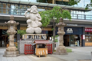 Een traditionele Japanse stenen sculptuur voor een modern gebouw met een bord waarop 'EDOCCO' staat.