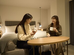 Two individuals seated at a round table in a hotel room with a bed in the background. - Hotel Resol Stay Akihabara (Tokyo)