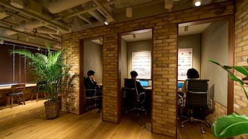 Un espacio de oficina con paredes de ladrillo, suelo de madera y varios puestos de trabajo.