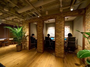 An office space with brick walls, wooden flooring, and multiple workstations. - Hotel Resol Stay Akihabara (Tokyo)