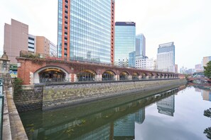 Un canal surmonté d’un pont en briques, avec des bâtiments modernes en arrière-plan.