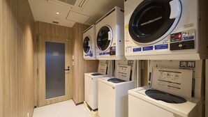 Een wasserette met meerdere wasmachines en drogers, houten wanden en een betegelde vloer.
