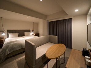 Een hotelkamer met een bed, een bank, een klein houten tafeltje, een nachtkastje en een lamp.