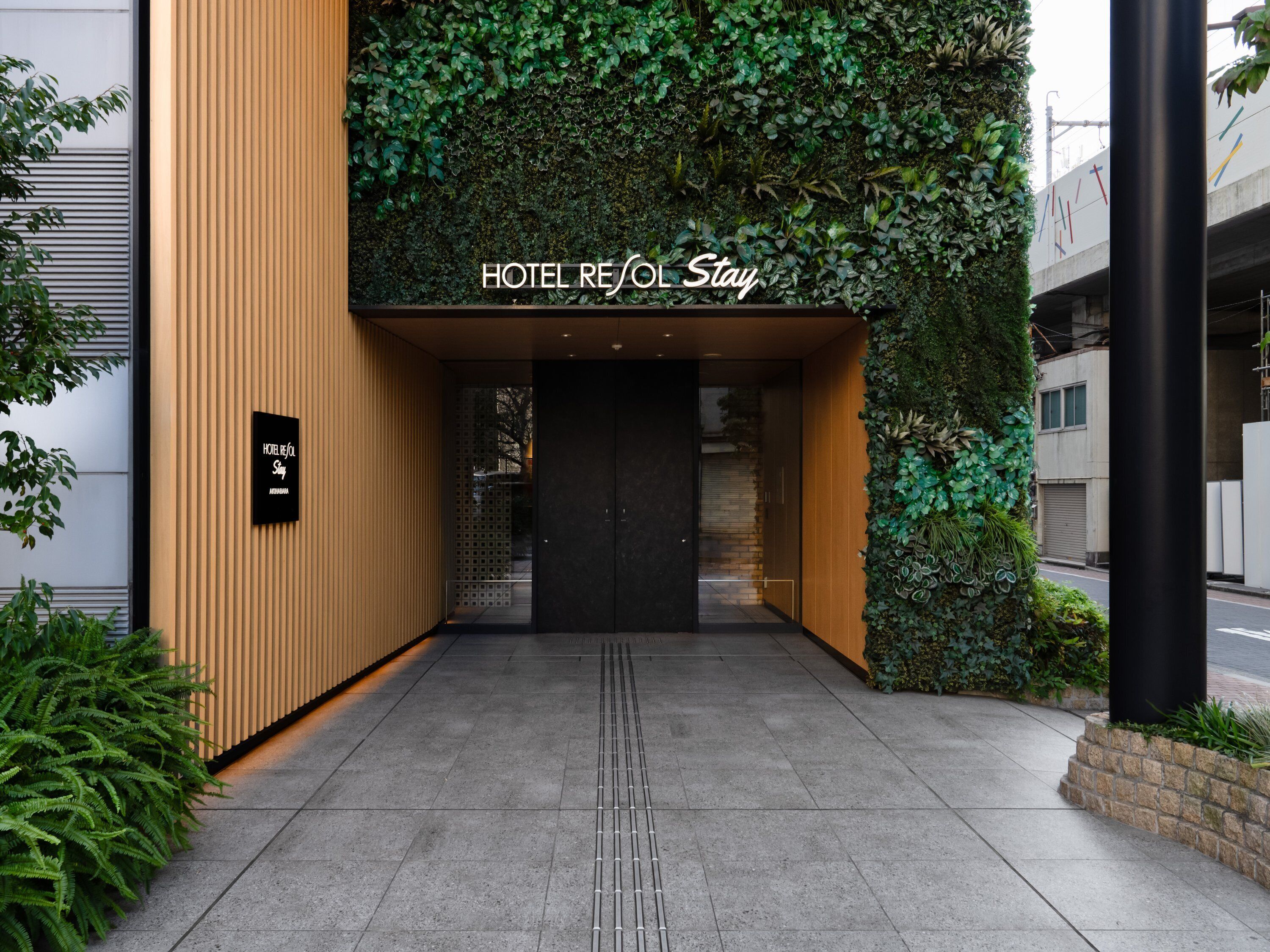 A hotel entrance with a sign reading 'HOTEL REJOL Stay' and a black sign below it.