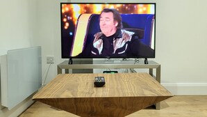Un téléviseur posé sur un meuble dans une pièce où se trouve une table en bois.