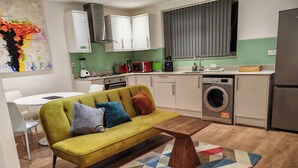 Un espace de vie compact comprenant un canapé, une table basse, un lave-linge et un coin repas.
