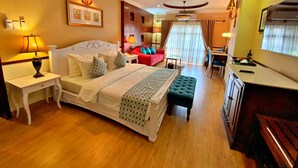 Ein Hotelzimmer mit einem großen Bett, Nachttischen, einem Schreibtisch, einem Sessel, einem kleinen Tisch, einer Couch und einem Fernseher.