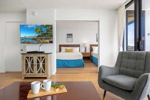 Quarto de hotel com cama, televisão, secretária e cadeira.