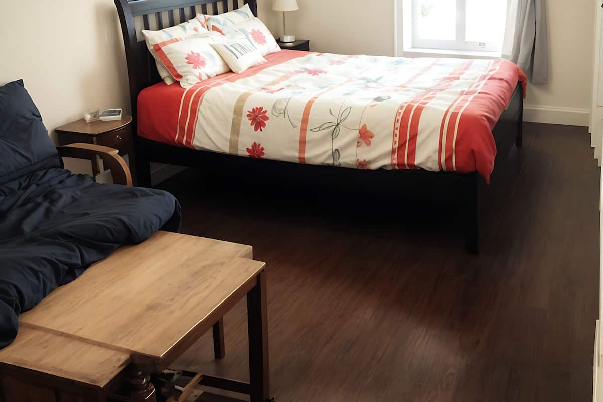Un dormitorio con cama, mesitas de noche, un banco de madera y una mesita auxiliar.