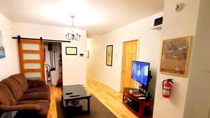 Un salón con un sofá marrón, una mesa de centro, un televisor y una chimenea.