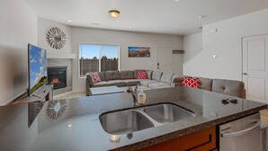 A modern kitchen with a double sink, a built-in oven, and a large window. - 3BR w fireplace, gaming TVs, mountain views! (Bellemont)