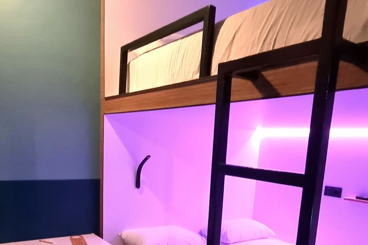 Dormitorio con literas, escritorio y un cesto de basura.