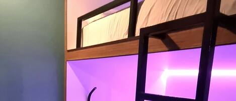 A bunk bed room with a desk and a trash bin.