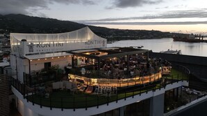 Hotel modern amb terrat bar que ofereix vistes a un cos d'aigua, amb seients a l'aire lliure i vista al port.
