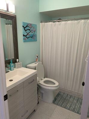 Bathroom features a toilet, sink, and shower curtain, with a painting above the sink.