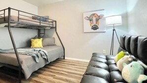 Um quarto com uma cama beliche, um sofá e uma luminária.