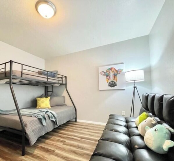 Una habitación con una litera, un sofá y una lámpara.