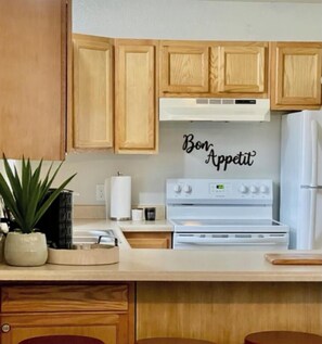 Una cocina con armarios de madera, una estufa blanca y un letrero que dice 'Bon Appetit' en la pared.