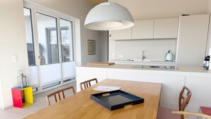 Une cuisine moderne avec une table à manger en bois, des chaises et un luminaire suspendu.