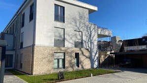 Un bâtiment moderne à deux étages, doté d’un toit plat, de grandes fenêtres et d’un petit balcon.