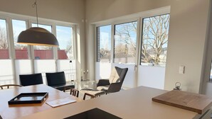 Une cuisine moderne dotée d’un îlot central, de grandes fenêtres et d’un coin repas avec des chaises.