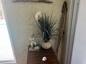 Uma pequena prateleira de madeira com uma estatueta de cerâmica, uma planta em vaso e um objeto decorativo.