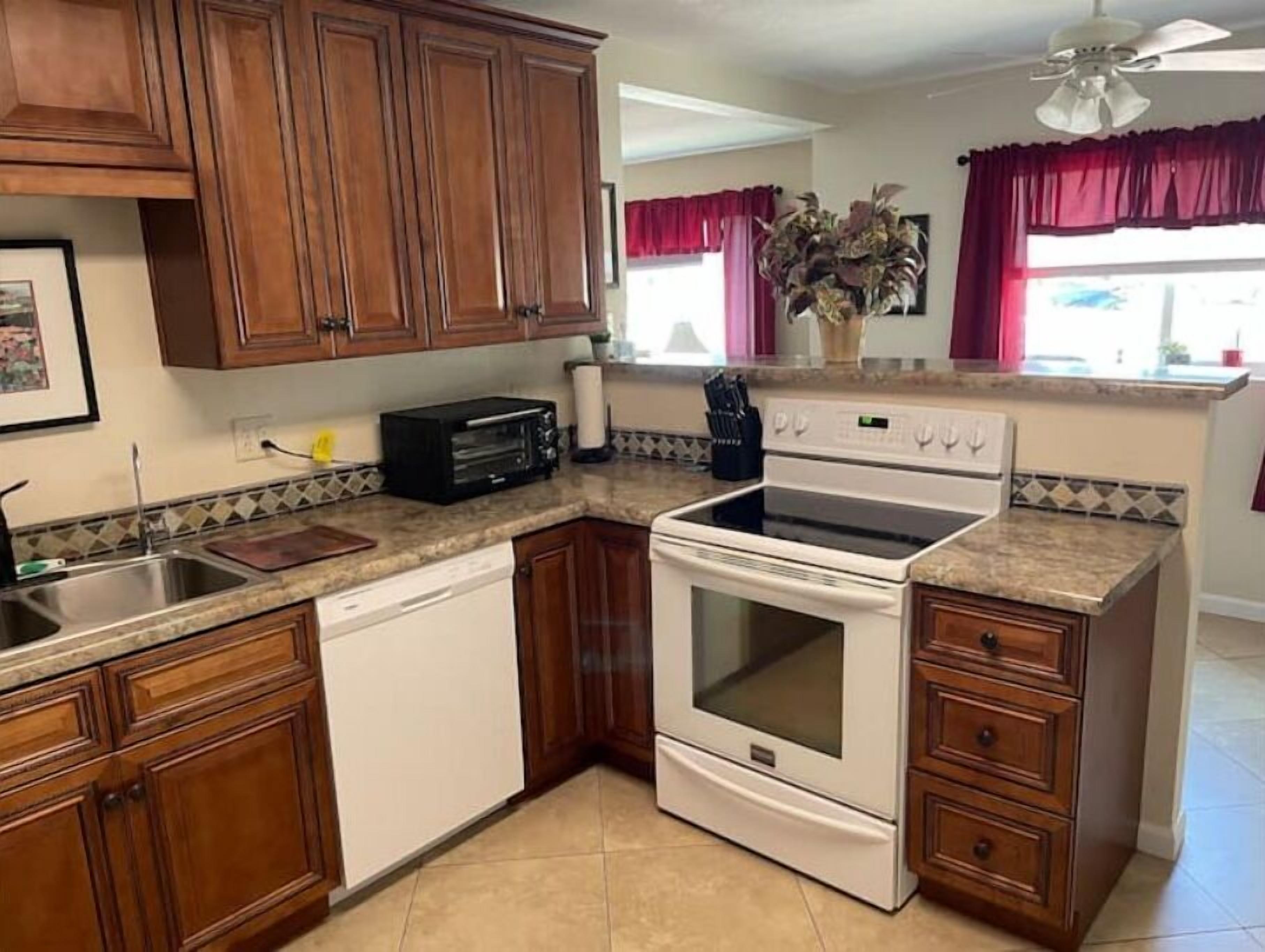 A kitchen with wooden cabinets, a white dishwasher, a stove, and a toaster.