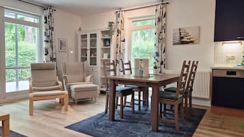 Een moderne woonkamer met een eettafel, stoelen, een bank en een kast.
