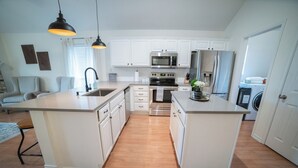 Une cuisine moderne avec des meubles blancs, des appareils en acier inoxydable et un îlot central.