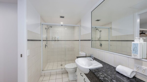 A modern bathroom with a glass-enclosed shower, a white sink, and a large mirror.