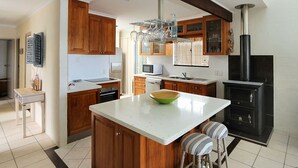 Una cocina con armarios de madera, encimera blanca, microondas, lavabo y estufa negra.