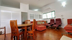 A living room with a wooden dining table, two wooden chairs, a red sofa, and two red armchairs.