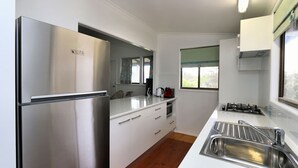 A modern kitchen with stainless steel appliances, white cabinetry, and a window providing natural light.