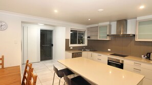 A modern kitchen with a central island, built-in appliances, and a dining area with a wooden table and chairs.