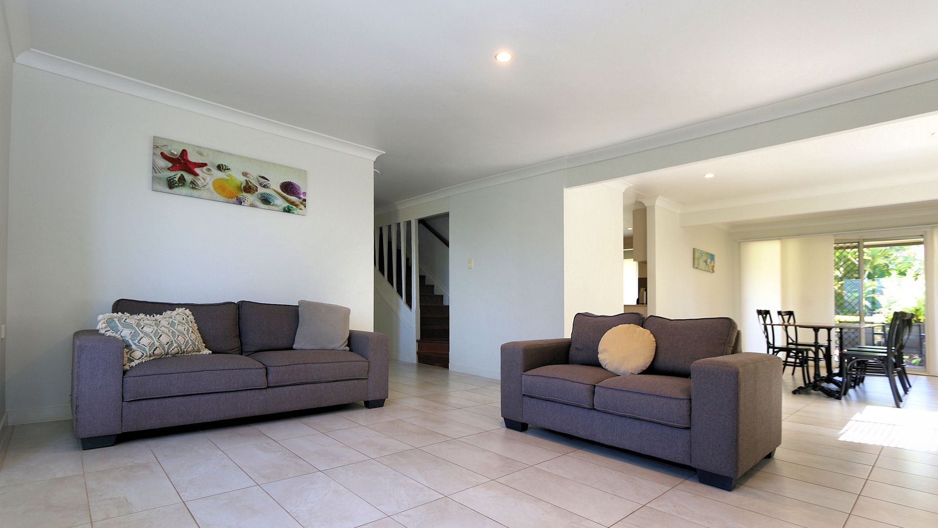 A spacious living area with two sofas, a staircase, and a dining area with chairs and a table.