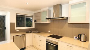A modern kitchen with stainless steel appliances, a window, and a view of greenery outside.