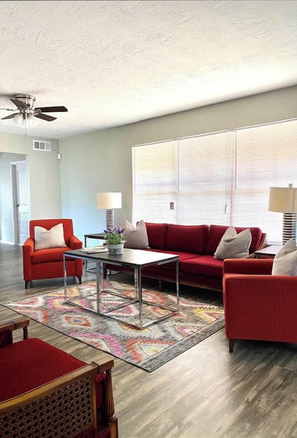 A living room with a red sofa set, a coffee table, and a patterned rug.
