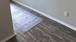 A hallway with a textured gray wall, a large abstract painting, and a patterned rug on a wooden floor. - Huge Private 3 Bedroom House Large Master Fenced Yard, Galveston, Kemah, Fishing (Texas City)