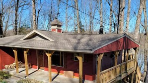 Un chalet rustique doté d’une véranda, d’une cheminée et d’une terrasse en bois.
