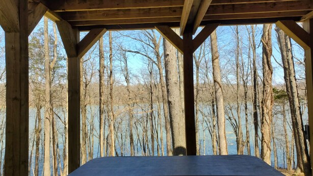 Un espace extérieur abrité offrant une vue sur un lac et des arbres.