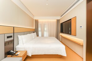 A hotel room with a bed, bedside table, phone, and a TV mounted on the wall.